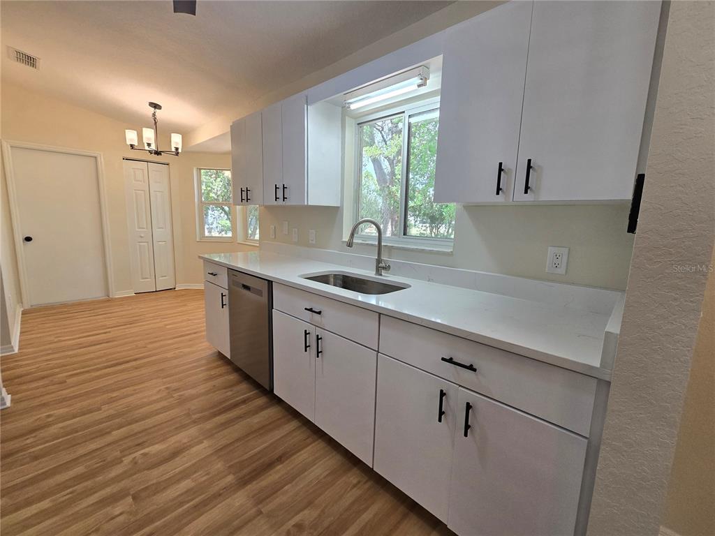 6121 Southwest 103rd Loop Ocala, FL 34476 - Photo 15 of 32 a kitchen with a sink cabinets wooden floor and a window