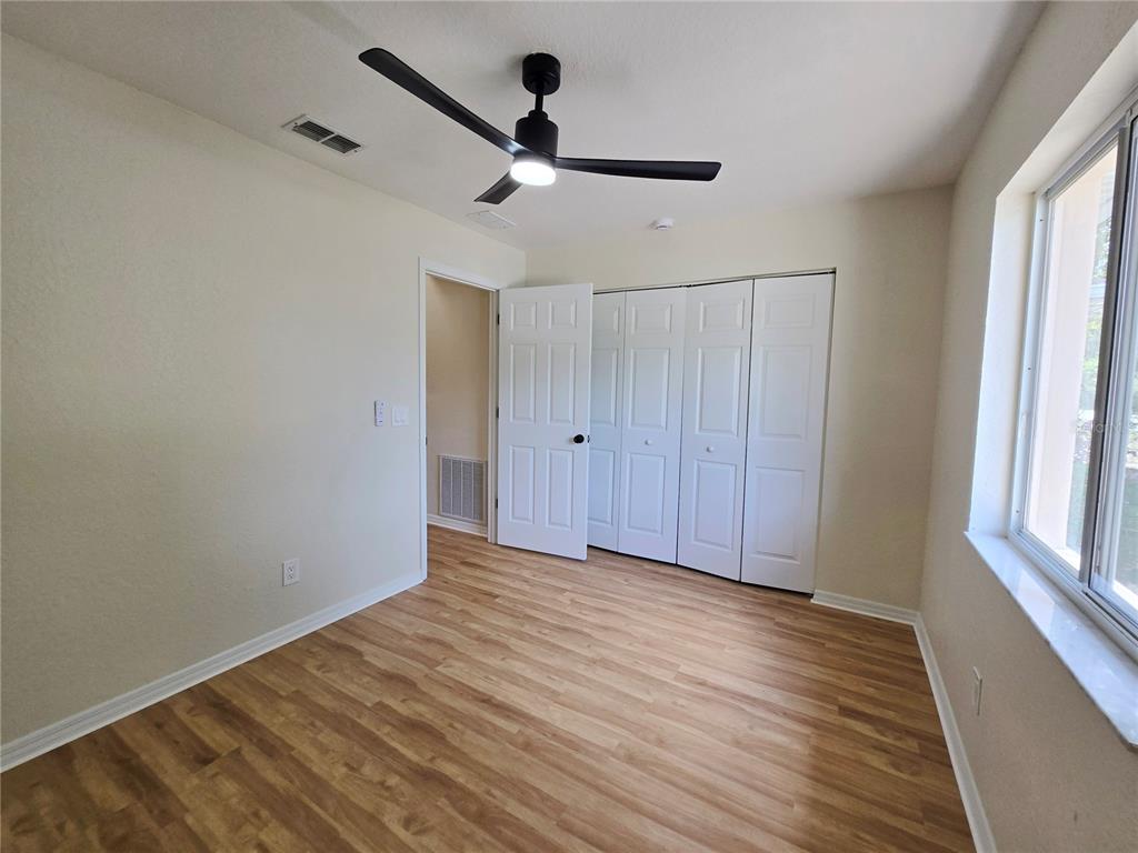 6121 Southwest 103rd Loop Ocala, FL 34476 - Photo 21 of 32 a view of an empty room with wooden floor and a window