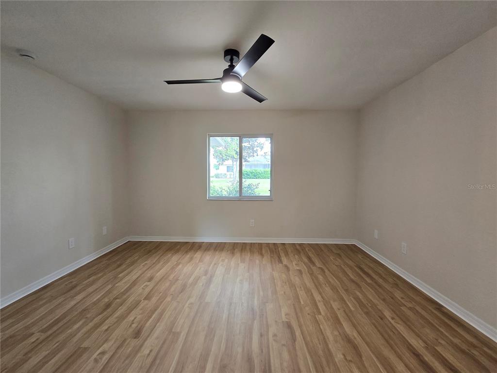 6121 Southwest 103rd Loop Ocala, FL 34476 - Photo 31 of 32 an empty room with wooden floor chandelier fan and windows