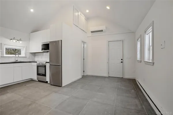 a view of a kitchen with a sink and dishwasher a refrigerator with white cabinets