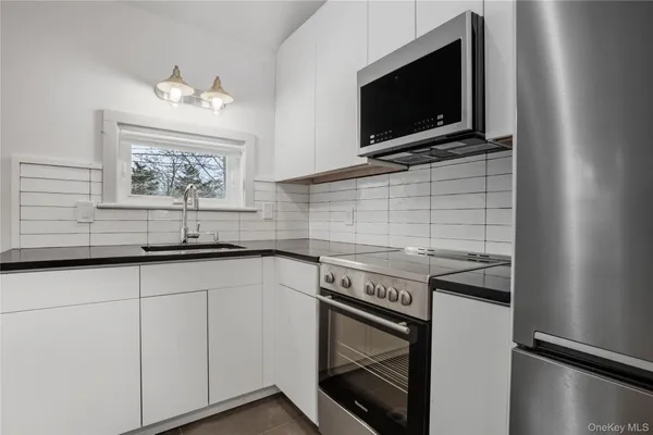 a kitchen with stainless steel appliances white cabinets and a stove top oven