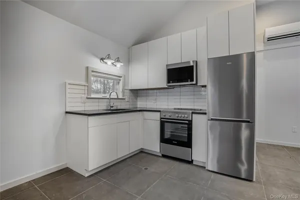 a kitchen with stainless steel appliances granite countertop a refrigerator a stove a microwave and a sink