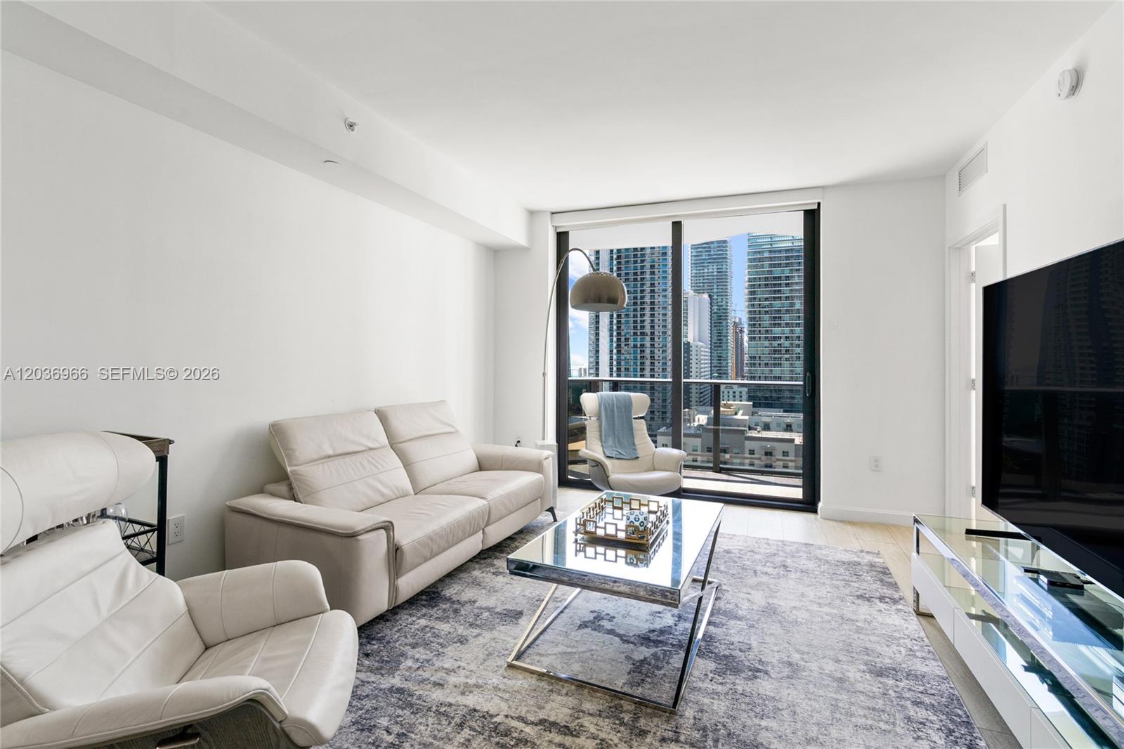 55 Southwest 9th Street, Unit 1904 Miami, FL 33130 - Photo 12 of 66 a living room with furniture a flat screen tv and a floor to ceiling window