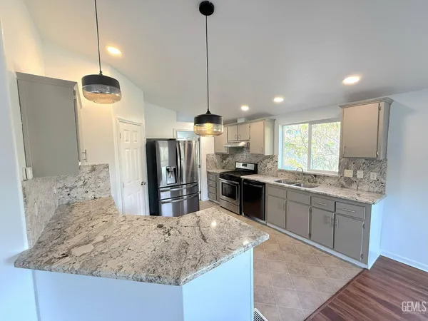 a kitchen with stainless steel appliances kitchen island granite countertop a refrigerator and stove