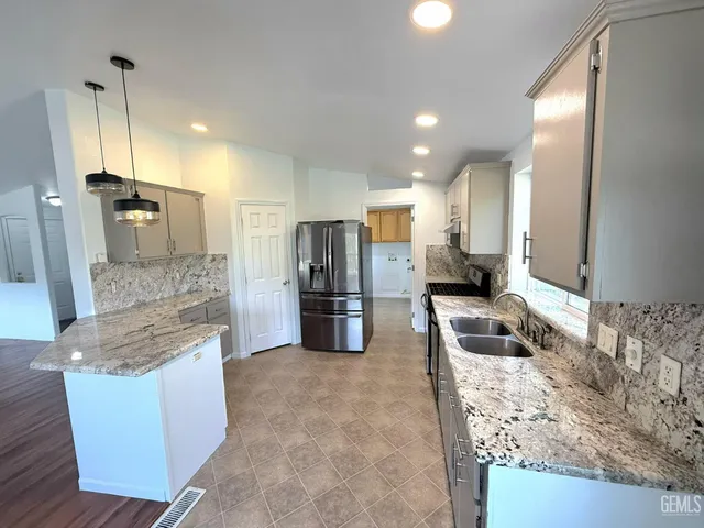 a kitchen with stainless steel appliances granite countertop a sink refrigerator and microwave