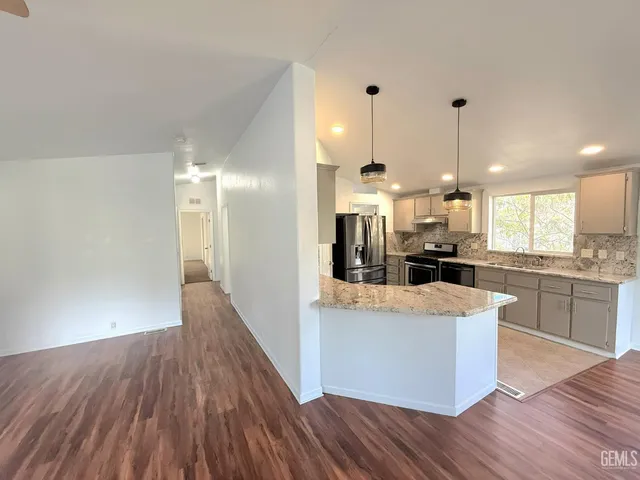 a large kitchen with stainless steel appliances kitchen island a large counter top and a wooden floors