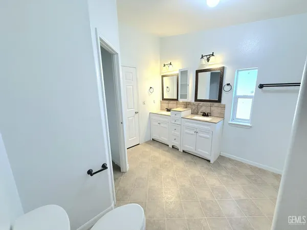 a bathroom with a granite countertop toilet sink and mirror