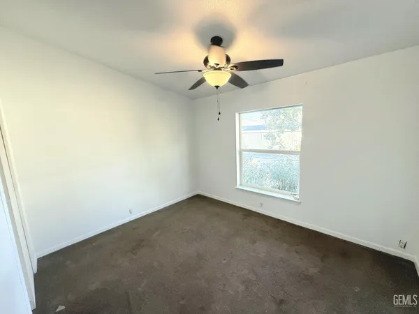 an empty room with a window and a fan