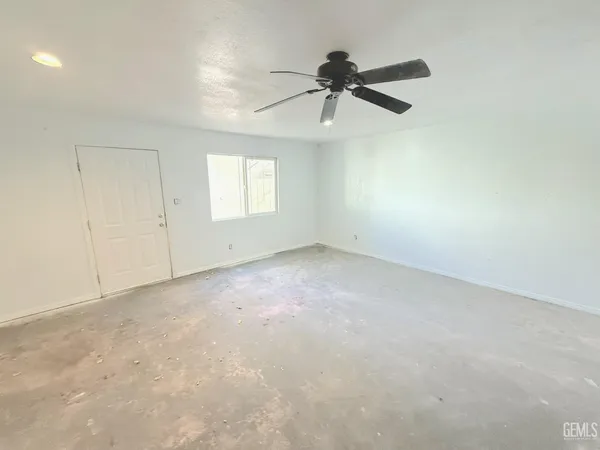 an empty room with a window and a fan