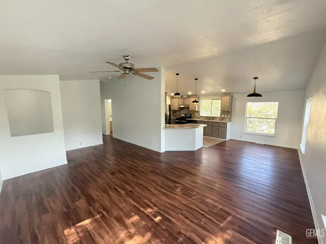 a view of a kitchen and an empty room with a window
