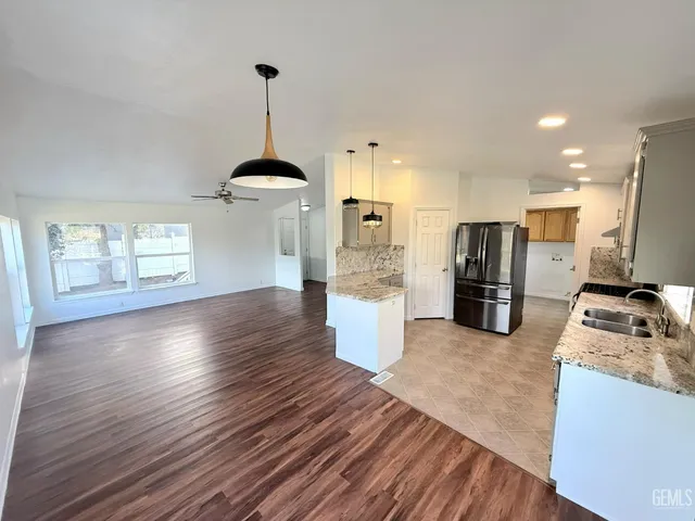 a kitchen with stainless steel appliances granite countertop a refrigerator a stove oven and a wooden floors