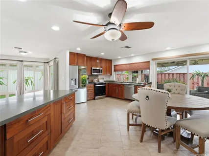 a kitchen with stainless steel appliances kitchen island granite countertop a table chairs and a refrigerator