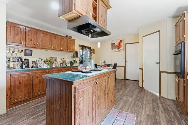 a kitchen with stainless steel appliances granite countertop a refrigerator a stove and a wooden floors