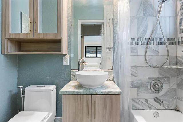 a bathroom with a granite countertop sink a toilet and a shower