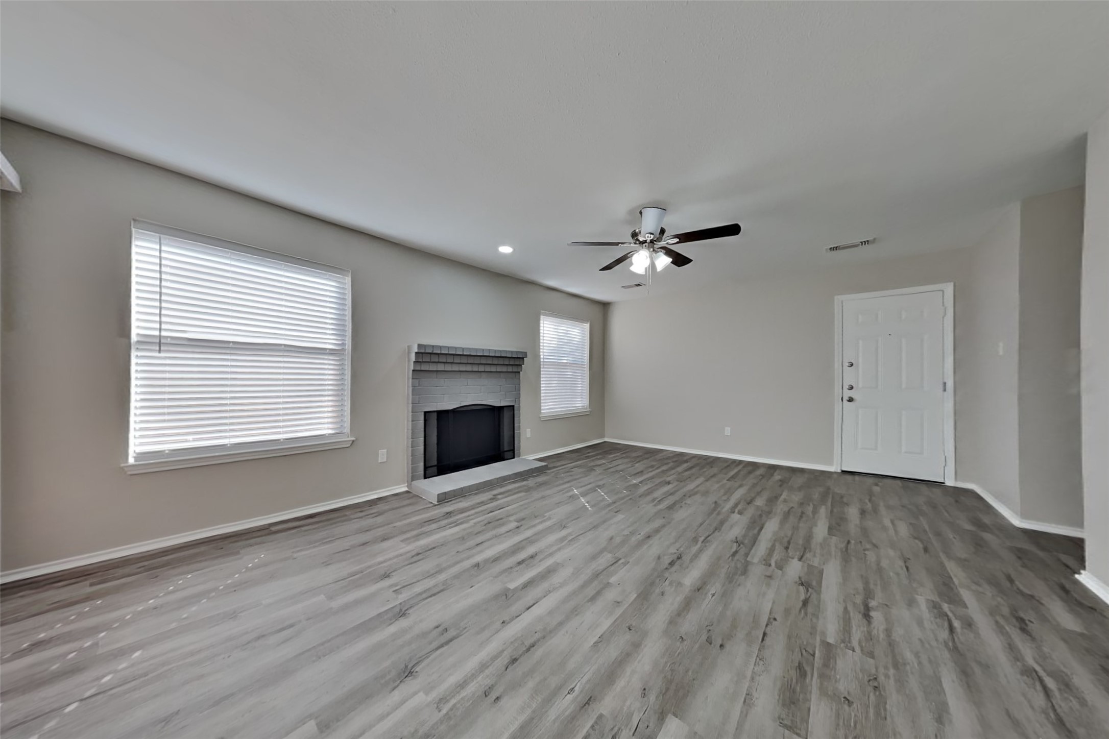 17030 Highworth Drive Spring, TX 77379 - Photo 3 of 24 an empty room with wooden floor a ceiling fan white walls and windows