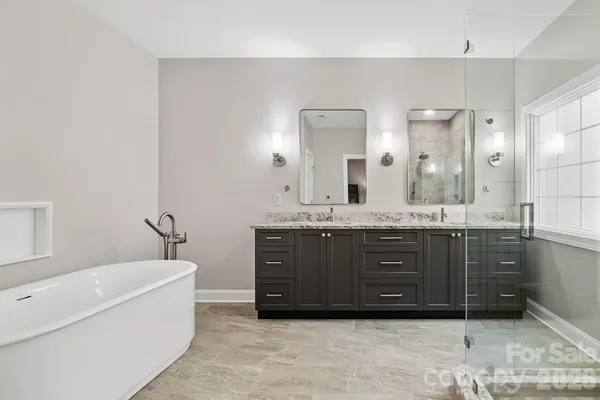 a bathroom with a tub a double vanity sink and a mirror