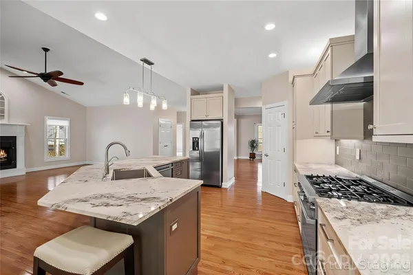 a kitchen with stainless steel appliances kitchen island granite countertop a table chairs in it and wooden floors
