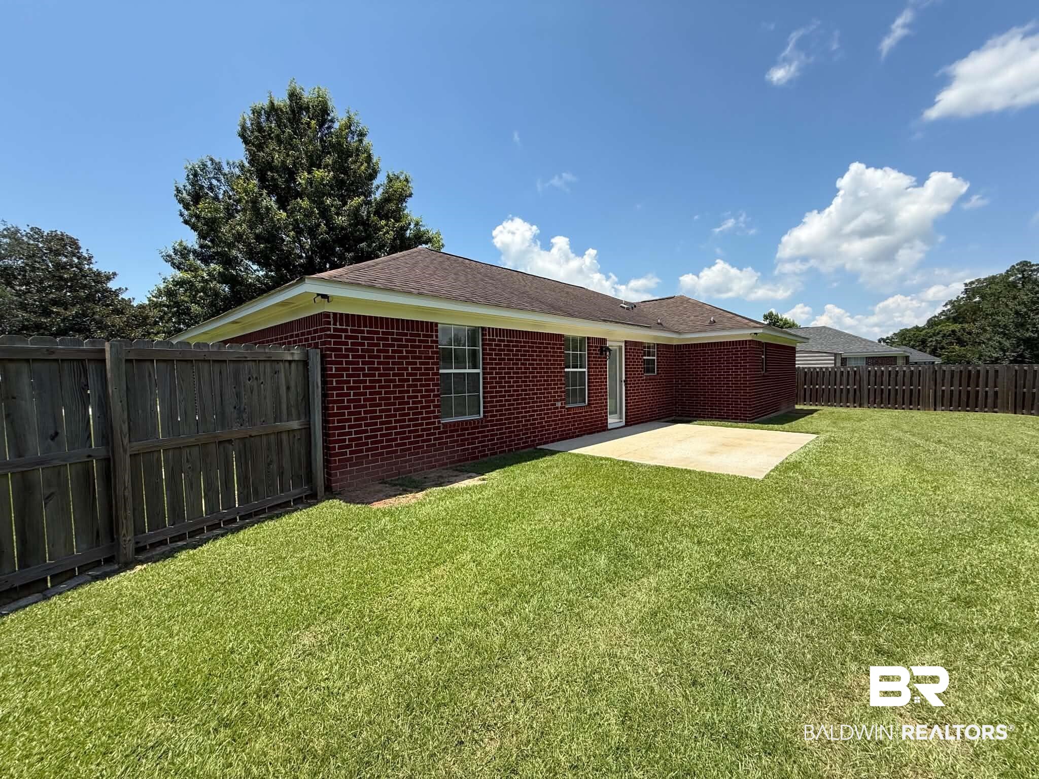 123 Pennbrooke Loop Foley, AL 36535 - Photo 12 of 49 Expansive backyard featuring a large green lawn, a concrete patio, and a privacy fence enclosing the perimeter