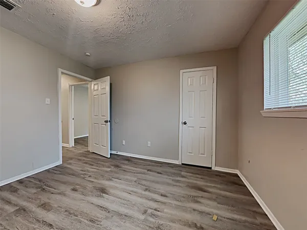 an empty room with wooden floor and windows