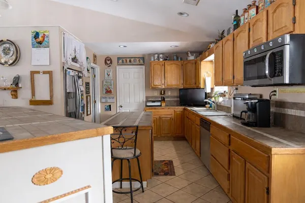 a kitchen with stainless steel appliances kitchen island granite countertop a sink a stove top oven a counter space and cabinets