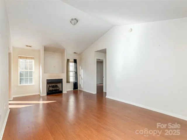 a view of an empty room with a fireplace and wooden floor