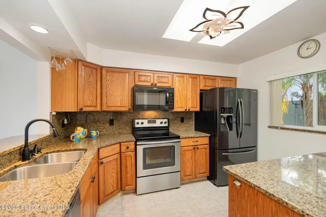 a kitchen with granite countertop a sink stainless steel appliances and window