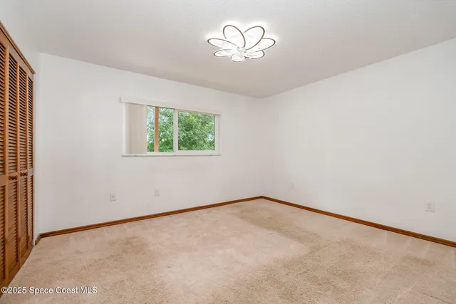 an empty room with a chandelier fan and window