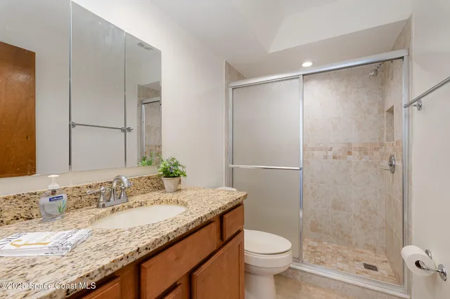 a bathroom with a granite countertop sink toilet and shower