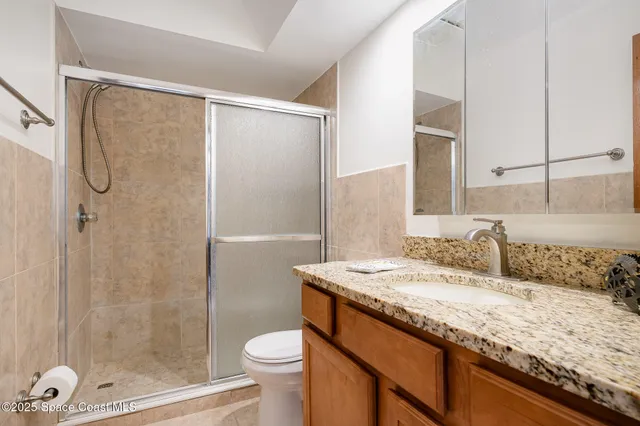 a bathroom with a granite countertop sink toilet and shower
