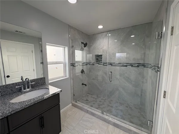 a bathroom with a granite countertop sink mirror and shower