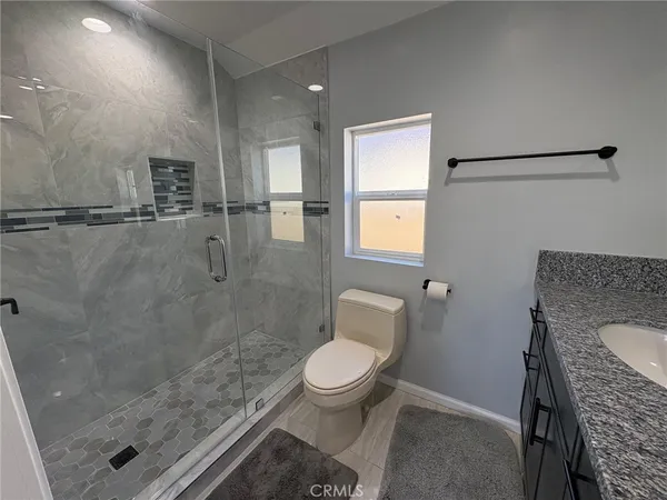 a bathroom with a granite countertop shower a toilet and a sink