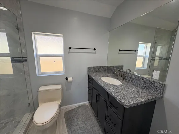a bathroom with a granite countertop toilet sink and mirror