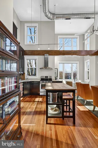 a dining hall with stainless steel appliances granite countertop a stove and a dining table with wooden floor