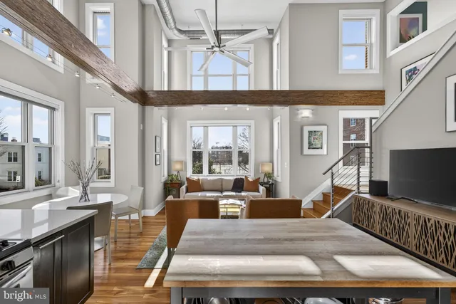 a living room with furniture a flat screen tv and large windows