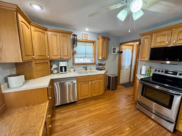 a kitchen with stainless steel appliances a stove a sink dishwasher a refrigerator white cabinets and wooden floor