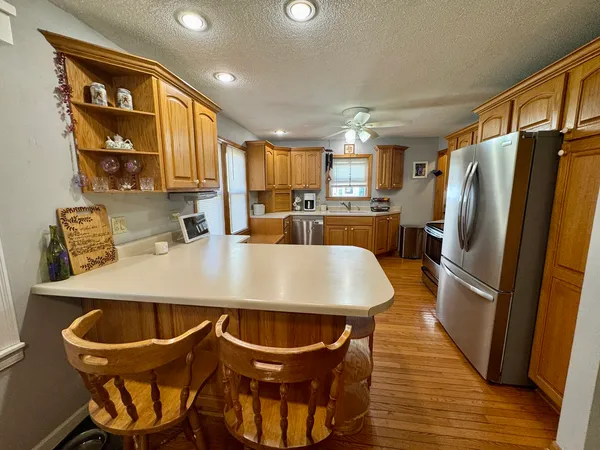 a kitchen with stainless steel appliances a dining table chairs and refrigerator