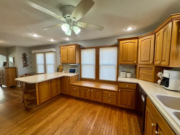 a large kitchen with a large window a sink dishwasher stove and refrigerator with wooden floor