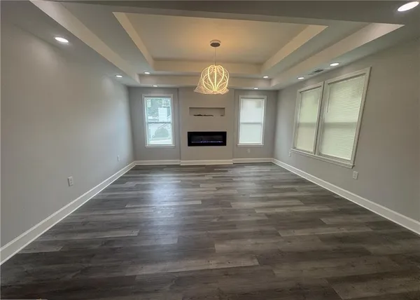 an empty room with wooden floor fireplace and windows
