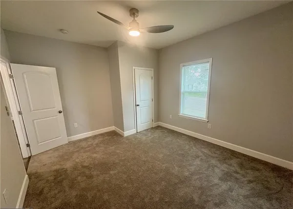 an empty room with windows and fan