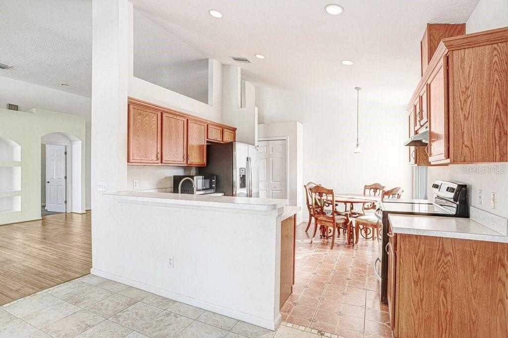 2412 Durant Road Valrico, FL 33594 - Photo 8 of 26 a kitchen with stainless steel appliances granite countertop a stove top oven a sink a dining table and chairs with wooden floor