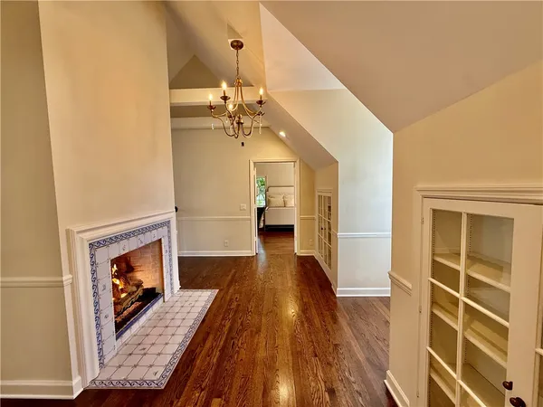 a hallway with a fireplace a chandelier and wooden floor