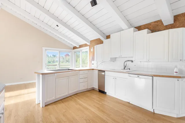 a large white kitchen with sink and window