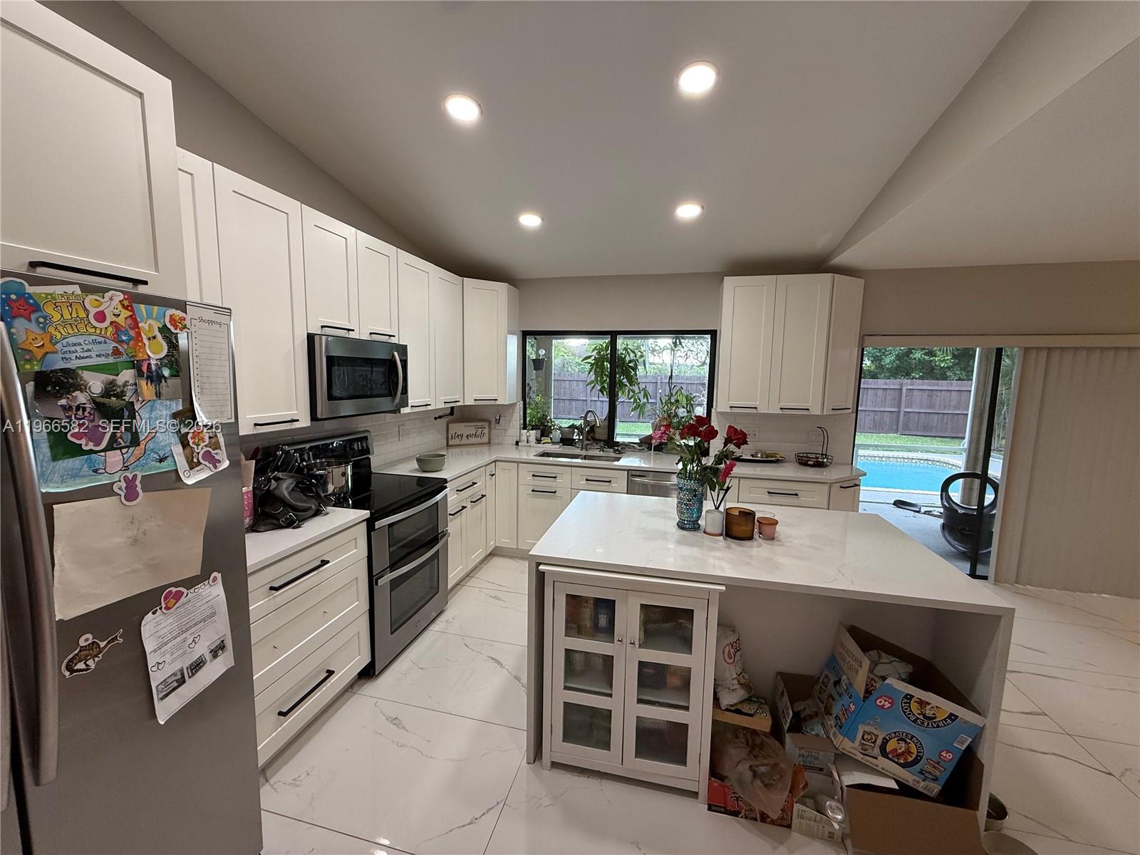 20888 Sugarloaf Lane Boca Raton, FL 33428 - Photo 8 of 25 a large kitchen with kitchen island a stove a sink a dining table and chairs