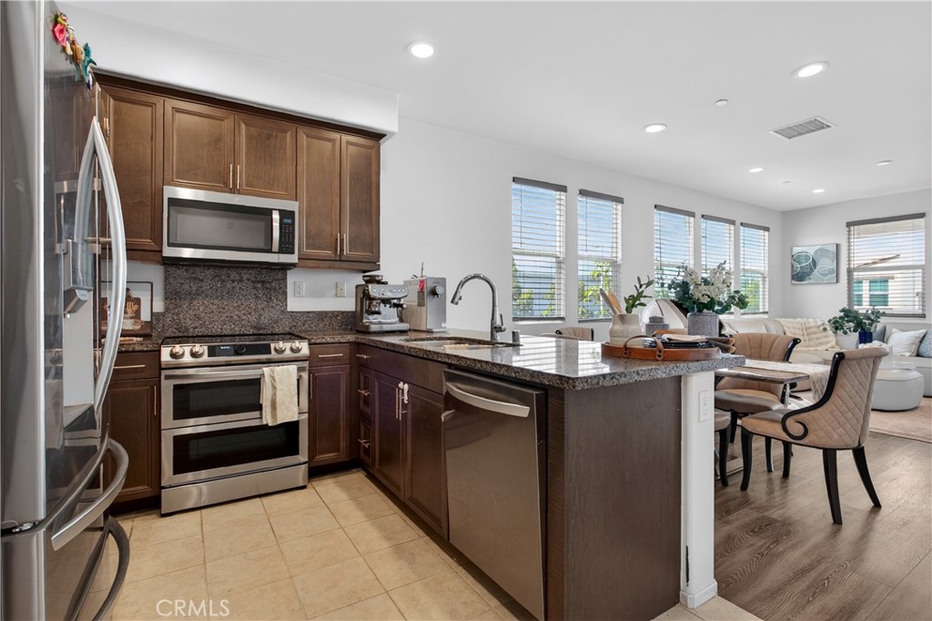 5796 Spring Street Buena Park, CA 90621 - Photo 9 of 33 a kitchen with kitchen island granite countertop a stove top oven a sink dishwasher a dining table and chairs with wooden floor