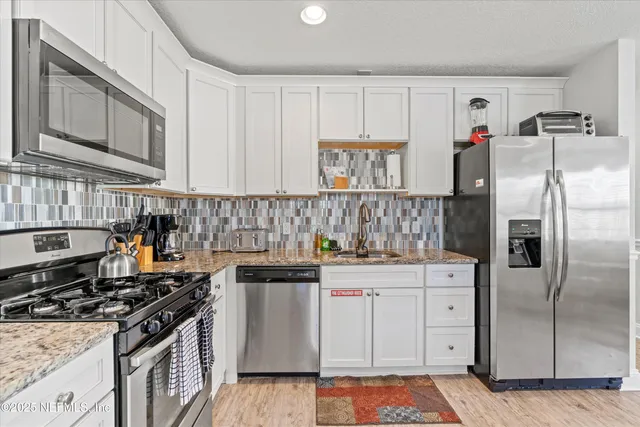 a kitchen with stainless steel appliances kitchen island granite countertop a table chairs sink and cabinets