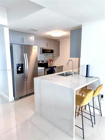 a kitchen with stainless steel appliances a refrigerator a stove a sink a dining table and chairs