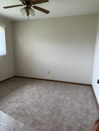 an empty room with a ceiling fan and carpet