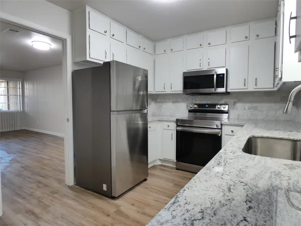 a kitchen with granite countertop a refrigerator stove and microwave