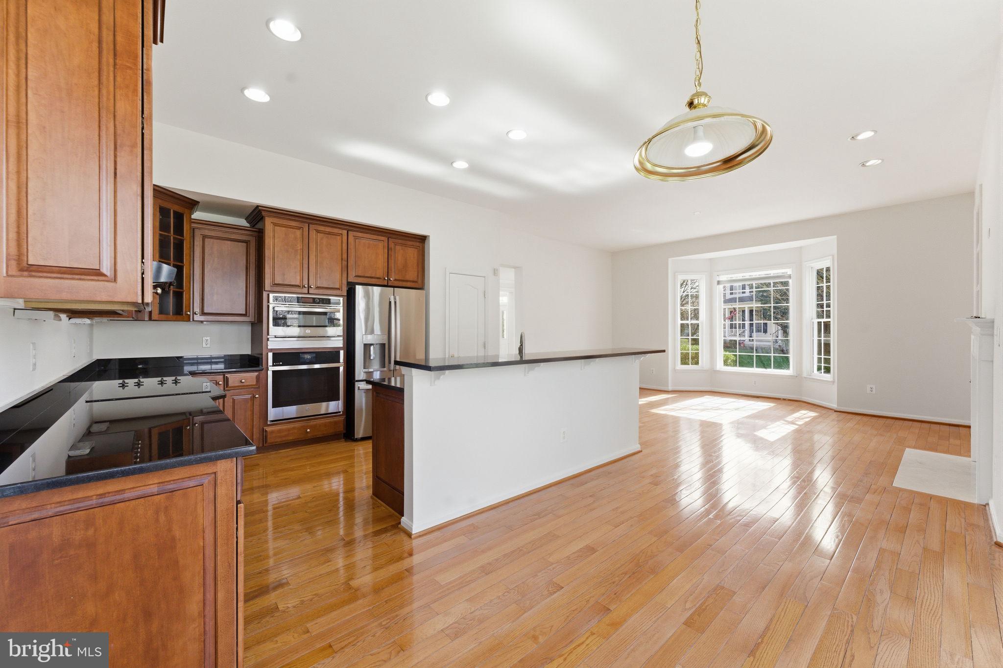 43358 Fullerton Street Ashburn, VA 20147 - Photo 17 of 54 a kitchen with stainless steel appliances granite countertop a stove a sink and a refrigerator with wooden floors