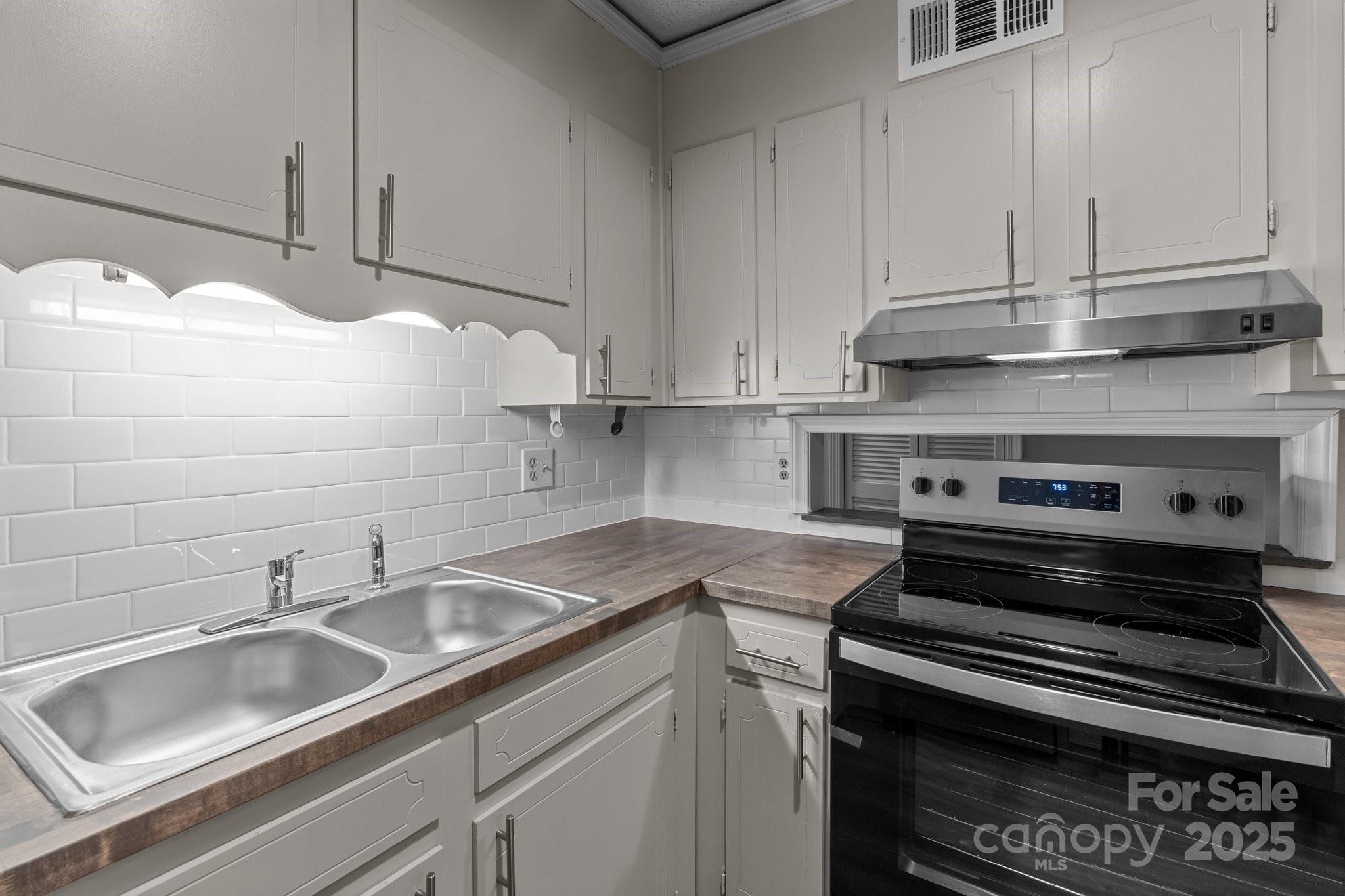 140 Lake Concord Road Northeast, Unit D9 Concord, NC 28025 - Photo 7 of 28 a kitchen with granite countertop a sink stove and cabinets